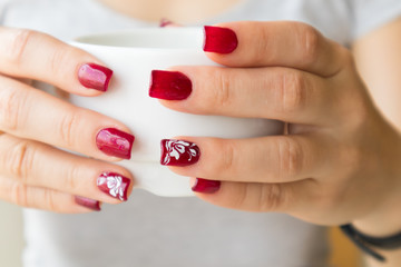 Woman's elegant red manicure and cup of green tea with lemon in cafe.
