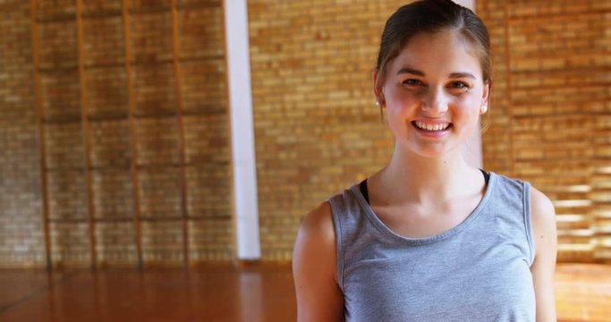 Schoolgirl standing with basketball in court 