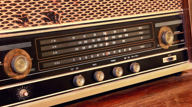 Close-up of vintage radio buttons and tuner control panel. Wooden brown antique retro old radio scale.