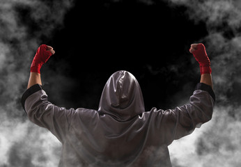 Female boxer with red boxing wraps wins the fight and bacame a champion. Victory pose. Black...