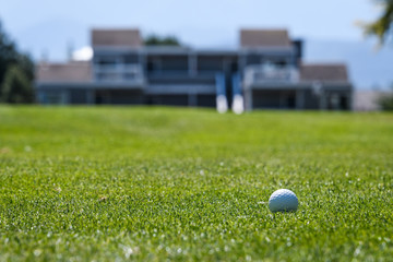 Golf ball in the fairway with out of focus building in the background
