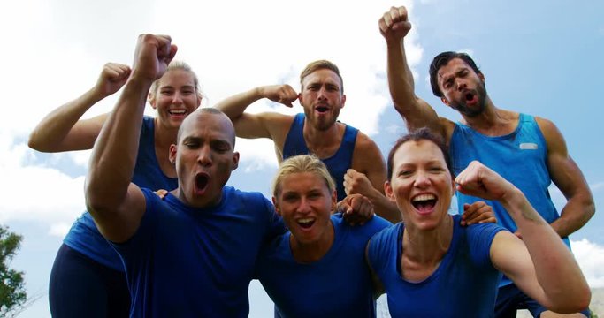 Group of fit people cheering together in boot camp 
