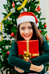 Asian girl holding gift box on the night of the celebration Christmas party with her family.