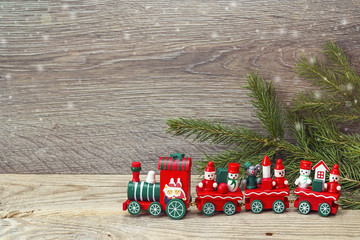 Red Christmas toy train with fir branches and copy space.