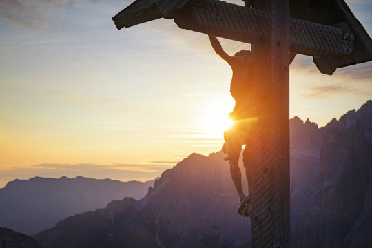 Crucifix on mountain at sunrise, Dolomites, Italy
