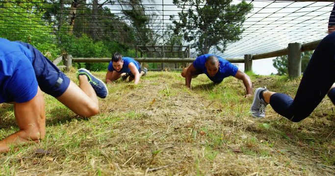 Fit people crawling under the net during obstacle course 