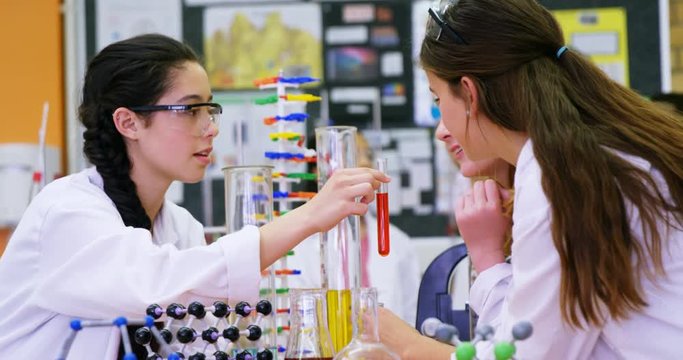 Schoolgirls smelling chemical in laboratory 