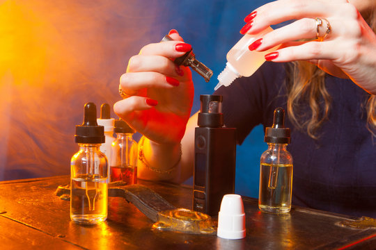 refueling a vape  device.  ripping his vape device, RDA or e-cigarette, close up, selective focus. The girl pours liquid into an electronic cigarette.