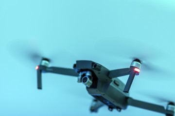 A blurry black unmanned radio-controlled drone on a blue background. Shallow depth of field.