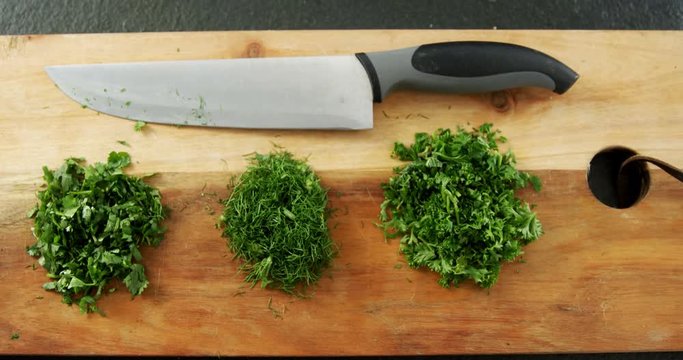Chopped herbs with knife on chopping board 