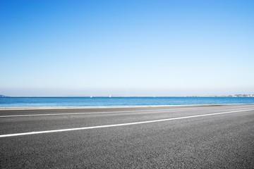 empty asphalt road with blue sea in blue sky