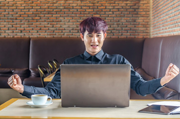 Sucessful happy businessman achiving his goal and showing fists  with laptop