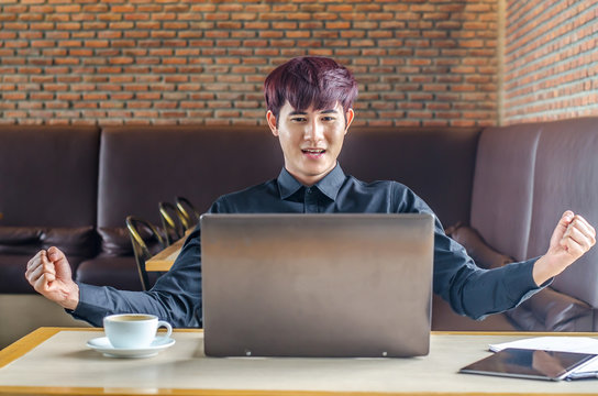Sucessful happy businessman achiving his goal and showing fists  with laptop