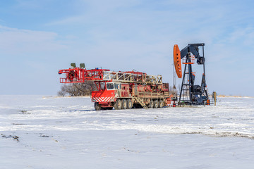 self-propelled drilling rig and pump jack in winter time on the field with snow