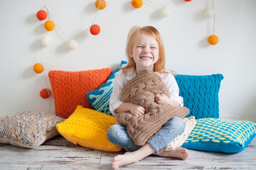 Red head girl among the colorful pillows laughs