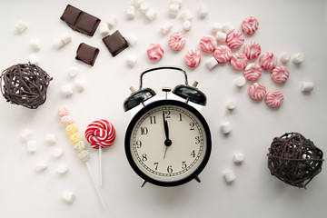 Alarm clock and Christmas candy on a white vintage background/ Christmas mood