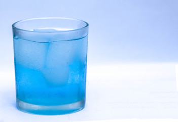 close-up Glass of blue water with ice cubes on white background with copy space