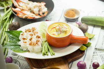 Curry crab, Seafood with Yellow curry sauce in orange ceramic pot, on tablecloths background