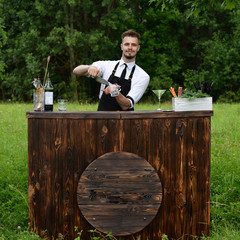 Catering bar service, bartender workplace. Handsome caucasian barman adding some ice cubes in a...
