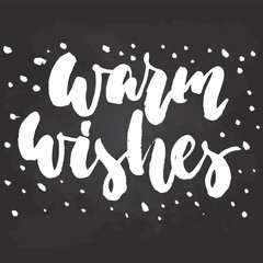Warm wishes - hand drawn Christmas and New Year winter holidays lettering quote isolated on the black chalkboard background. Fun brush ink inscription for greeting card or poster design.