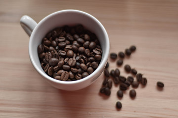 Cup full of coffee beans at wooden background/ top view