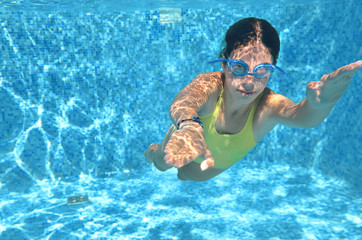 Young girl swimmer swimming under water in pool and has fun, teenager diving underwater, family vacation, sport and fitness concept
