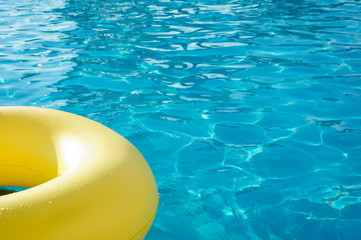 Yellow swim ring in a swimming pool with rippled water, background