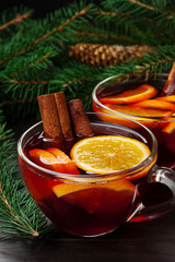 Christmas mood. Mulled wine in a glass cups on a wooden background with fir branches. Rustic style. Close up