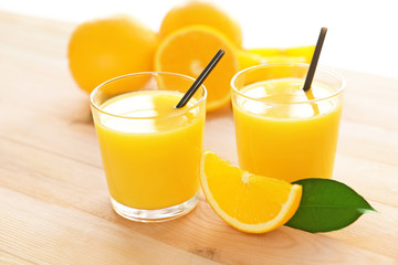 Glasses with yummy fresh orange juice on wooden table