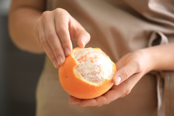 Woman peeling ripe orange, closeup