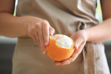 Woman peeling ripe orange, closeup