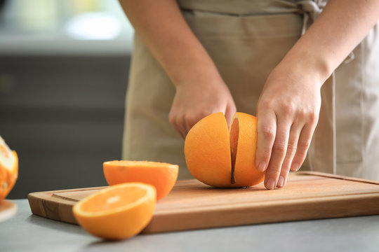 Woman cutting ripe orange in kitchen