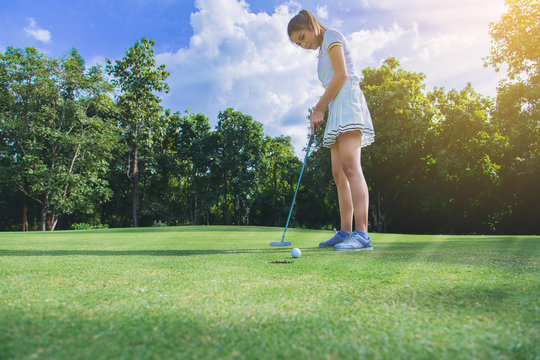 Pretty Woman Golfer Putting A Golf Ball Into Hole.