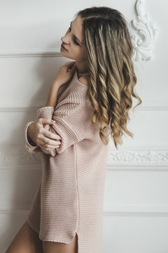 Sensual tenderness woman in light pink sweater at white antic interior