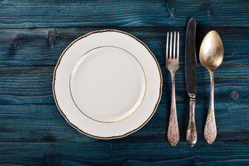Plate and old cutlery. On a wooden background. Top view. Free space for text.