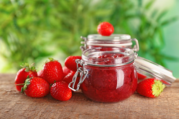 Jar of homemade jam and fresh strawberries on wooden table