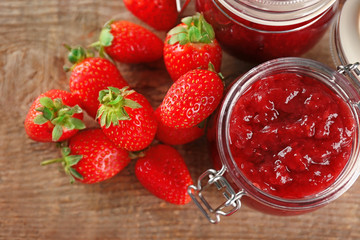Jar of homemade jam and fresh strawberries on wooden table
