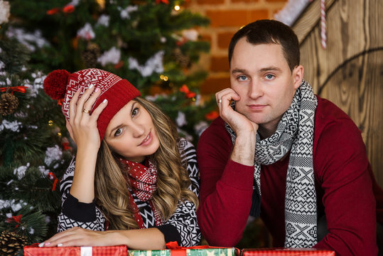 A happy woman opens New Year's gifts, and her sad husband looks at it. Expensive christmas gifts
