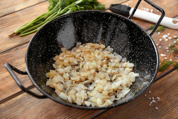 Dish with fried onion on wooden table