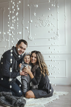 Family Dressed In Scandinavian Style In White Interior With Winter Decorated Location