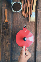 Coffee beans with ground coffee in wooden spoon and cinnamon, red kettle on the side on wooden background