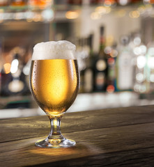 Frosty glass of light beer on the bar counter.