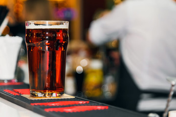 Dark beer in a glass on a white bar