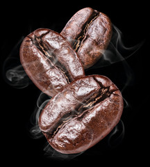 Three roasted coffee beans on the black background.