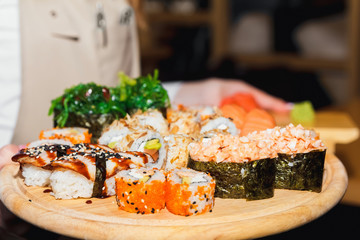 Sushi california salmon on a white rectangular plate in the waiter's hand close-up