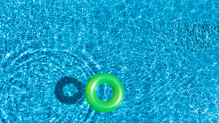 Fototapeta na wymiar Aerial view of colorful inflatable ring donut toy in swimming pool water from above, family vacation concept background 