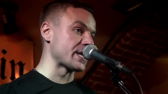 Portrait handsome musician singing song in microphone on rock consert at stage