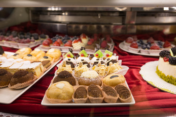 Different colorful Tasty beautiful cakes on a show-window in cafe