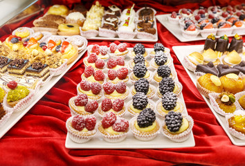 Different colorful Tasty beautiful cakes on a show-window in cafe