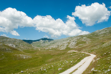 Mountain landscape with a dusty road and dramatic clouds